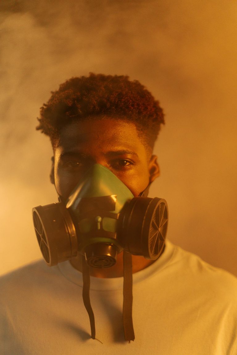 A conceptual image of a man wearing a respirator mask against a smoky backdrop.
